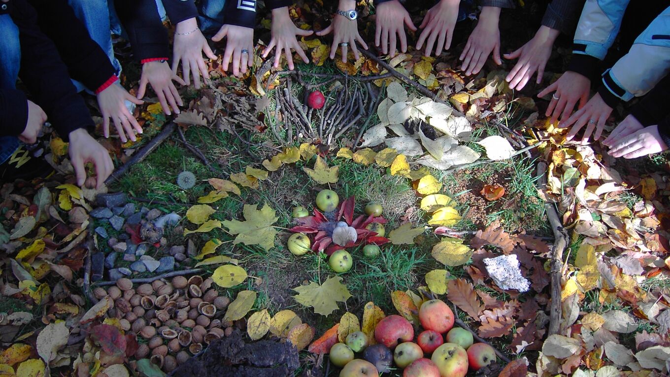 Ein herbstliches Mandala aus Naturmaterial wie Blätter, Zweige, Äpfel.